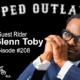 Dr. Glenn Toby in a navy suit and glasses, smiling with hands clasped — Moped Outlaws Podcast Episode 208